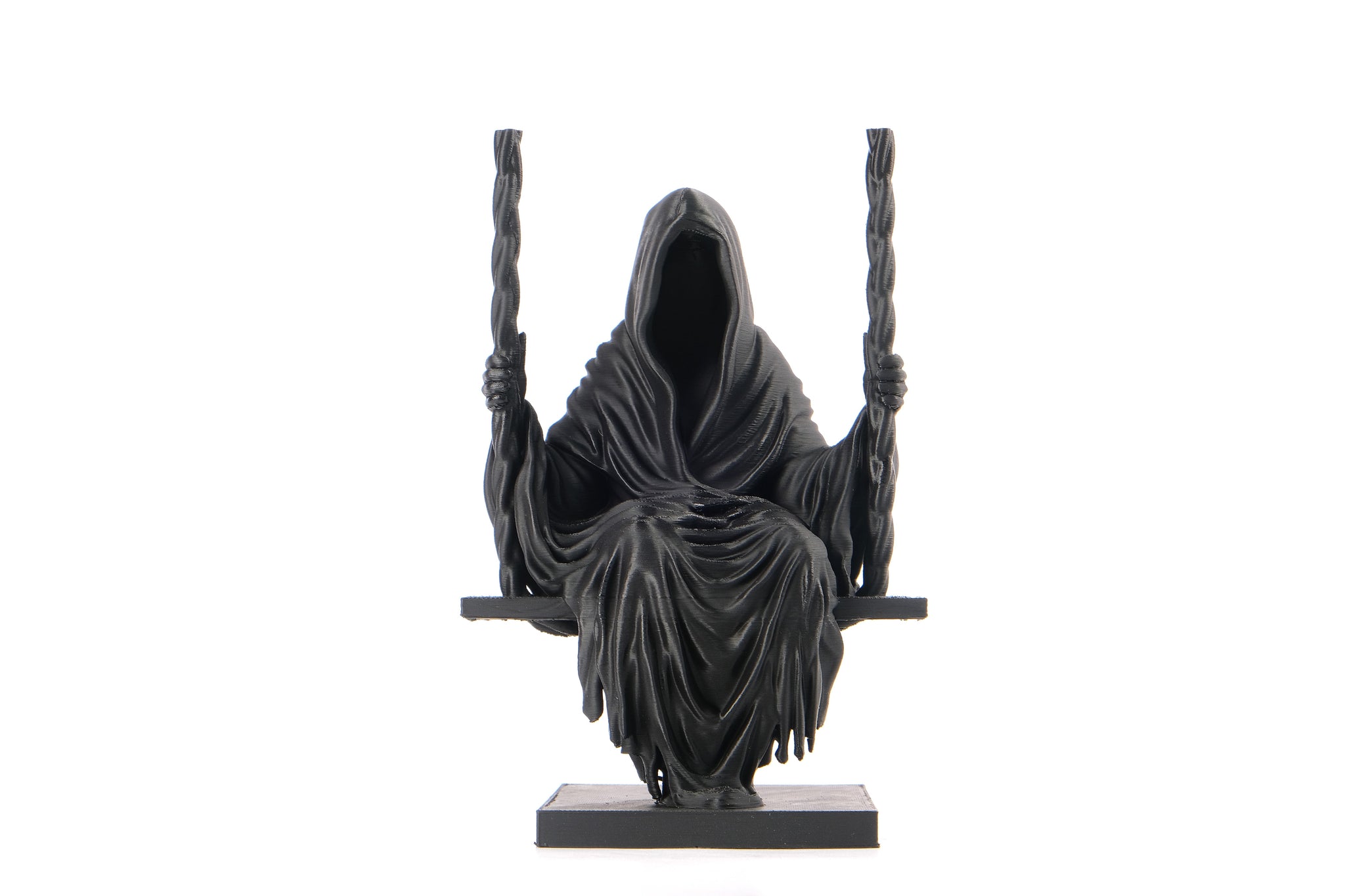 Dark gothic grim reaper sculpture styled on a dark wooden shelf with candles and moody decor