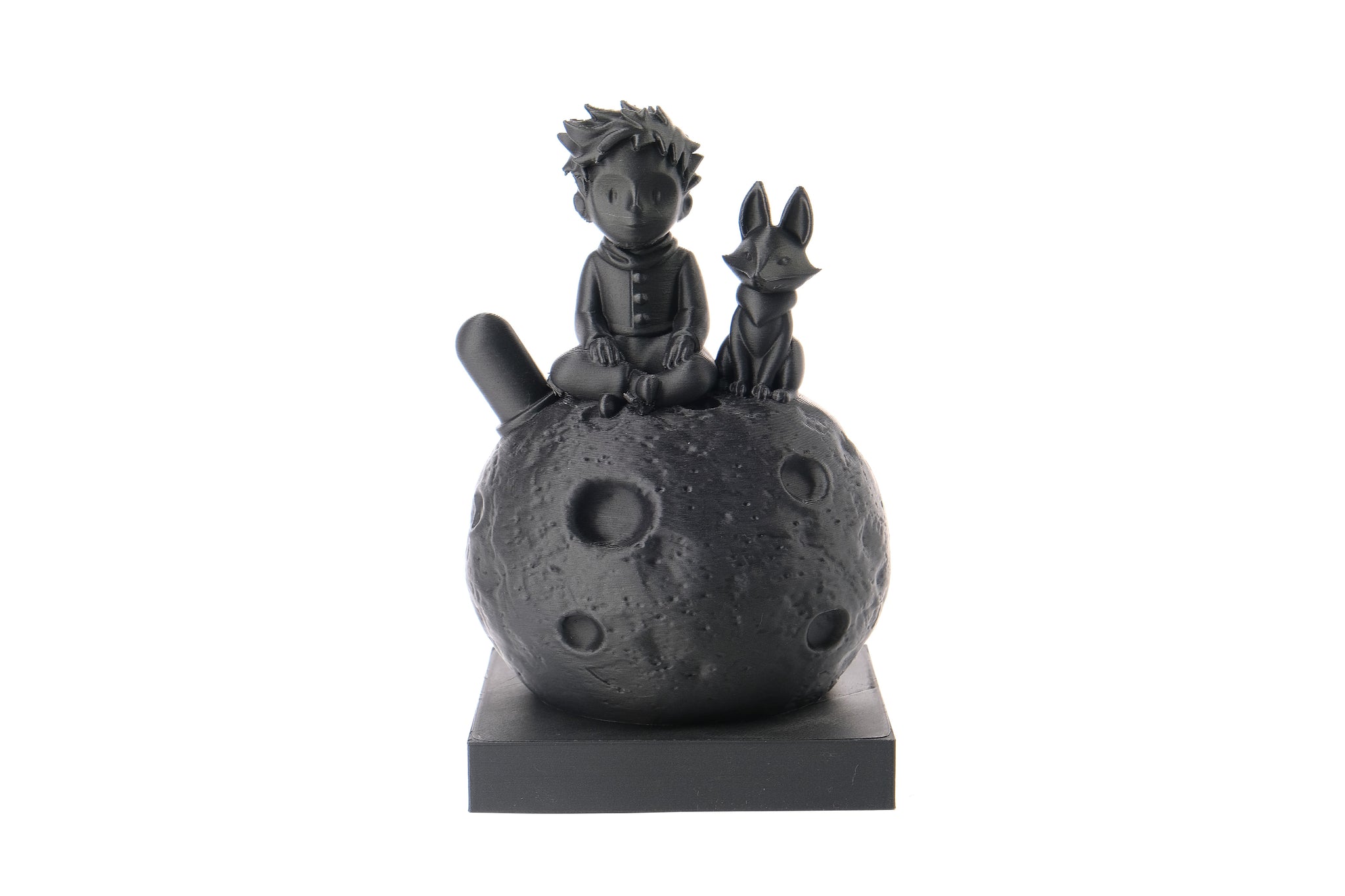 Little prince and fox sculpture styled on a wooden bookshelf beside books