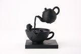 Tea Time Reverie sculpture styled on a dark shelf alongside books and minimal decor objects