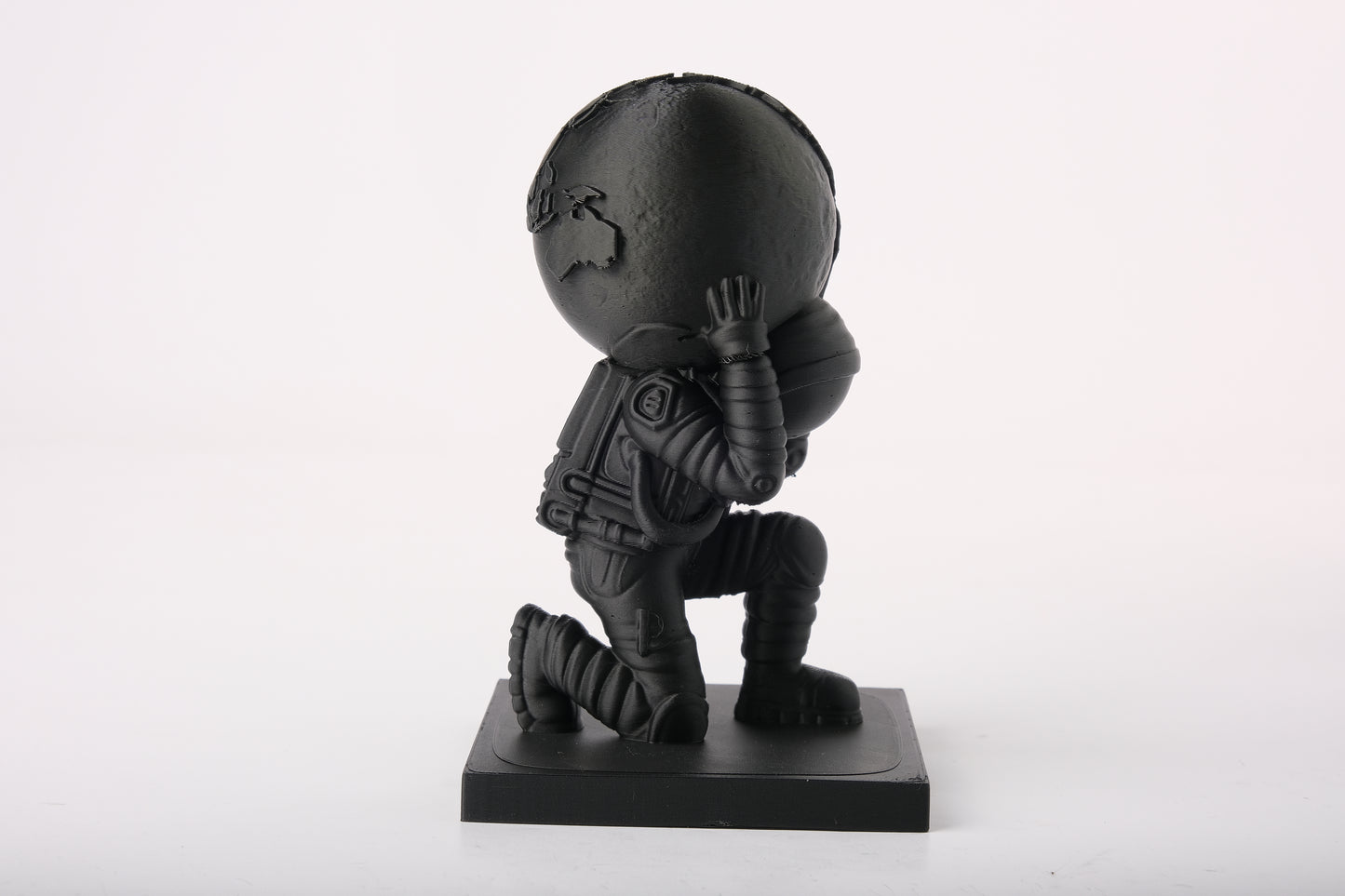Modern atlas astronaut statue styled on a minimalist desk with books and neutral decor