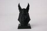 Anubis bust styled on a dark wooden shelf alongside candles and minimal decor objects