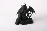Gothic demonic figure sculpture styled on a dark shelf alongside candles and moody decor