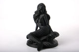 Mermaid bust sculpture styled on a wooden shelf alongside neutral ceramic objects and soft lighting