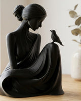 Minimalist woman and bird sculpture in white, front view on a light surface
