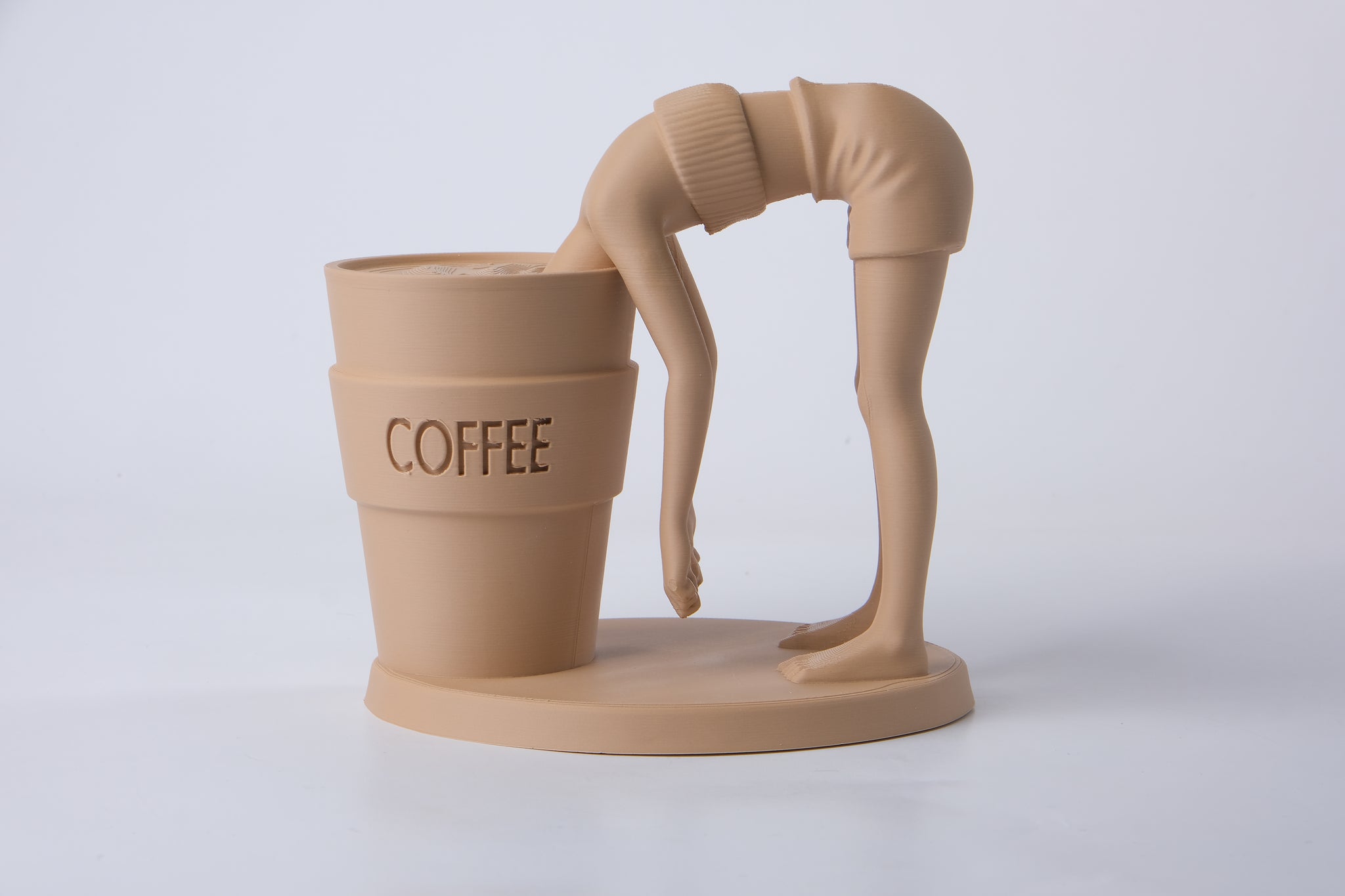 Surreal coffee sculpture styled on a wooden desk beside a ceramic mug and small plant