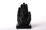 Buddha hand sculpture styled on a wooden shelf beside candles and dried botanicals in a calm meditation corner