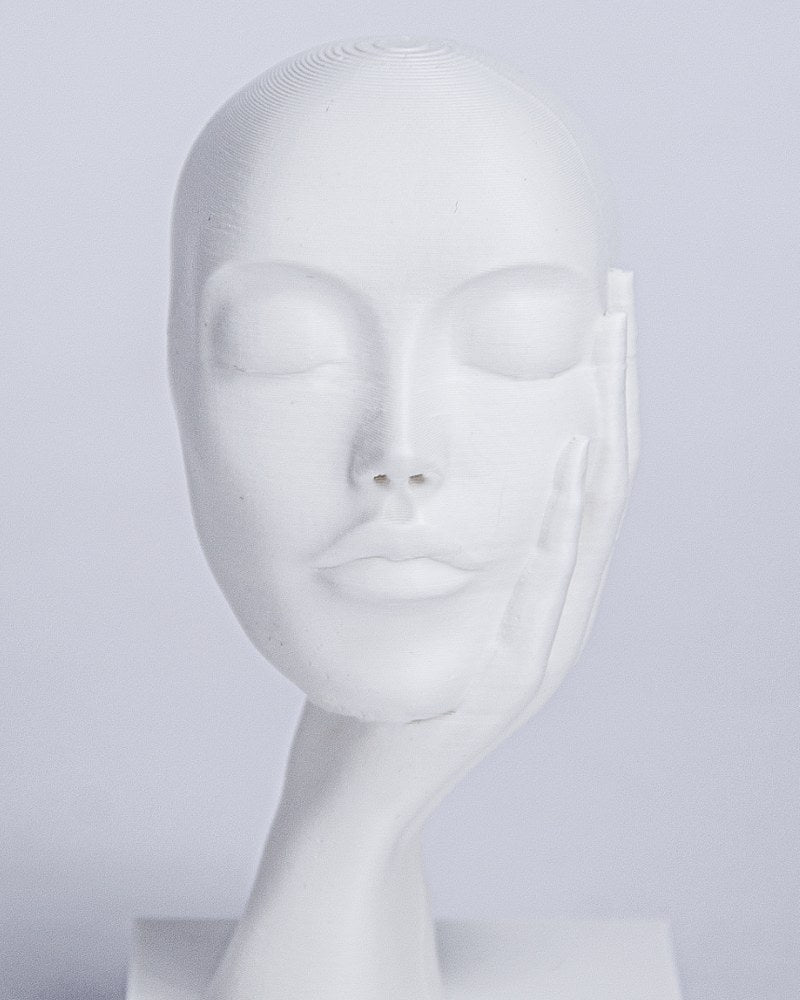 Close-up of Dreamer's Rest face sculpture showing closed eyes and hand cradling cheek, minimalist ansigt skulptur