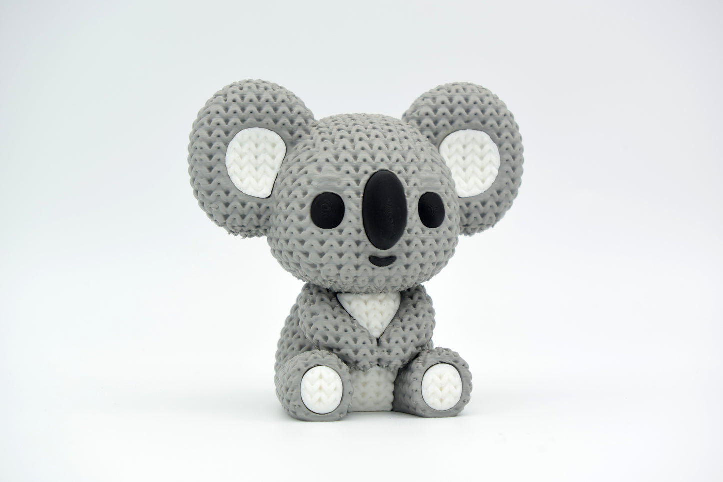 Texture detail of a knitted koala figure showing the looped yarn-like pattern across the rounded back and limbs