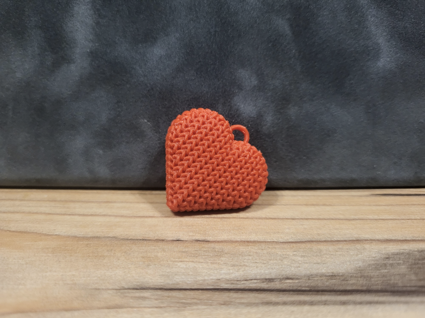Knitted heart keychain resting on a wooden surface beside a set of keys in a light Scandinavian home