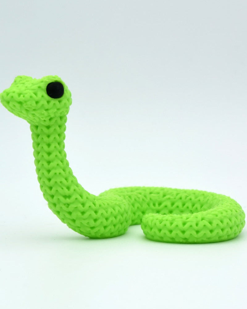 Close-up of a decorative knitted snake figurine with a soft crochet-look surface texture and small round eyes