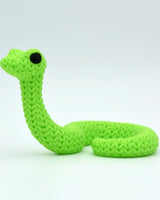 Close-up of a decorative knitted snake figurine with a soft crochet-look surface texture and small round eyes