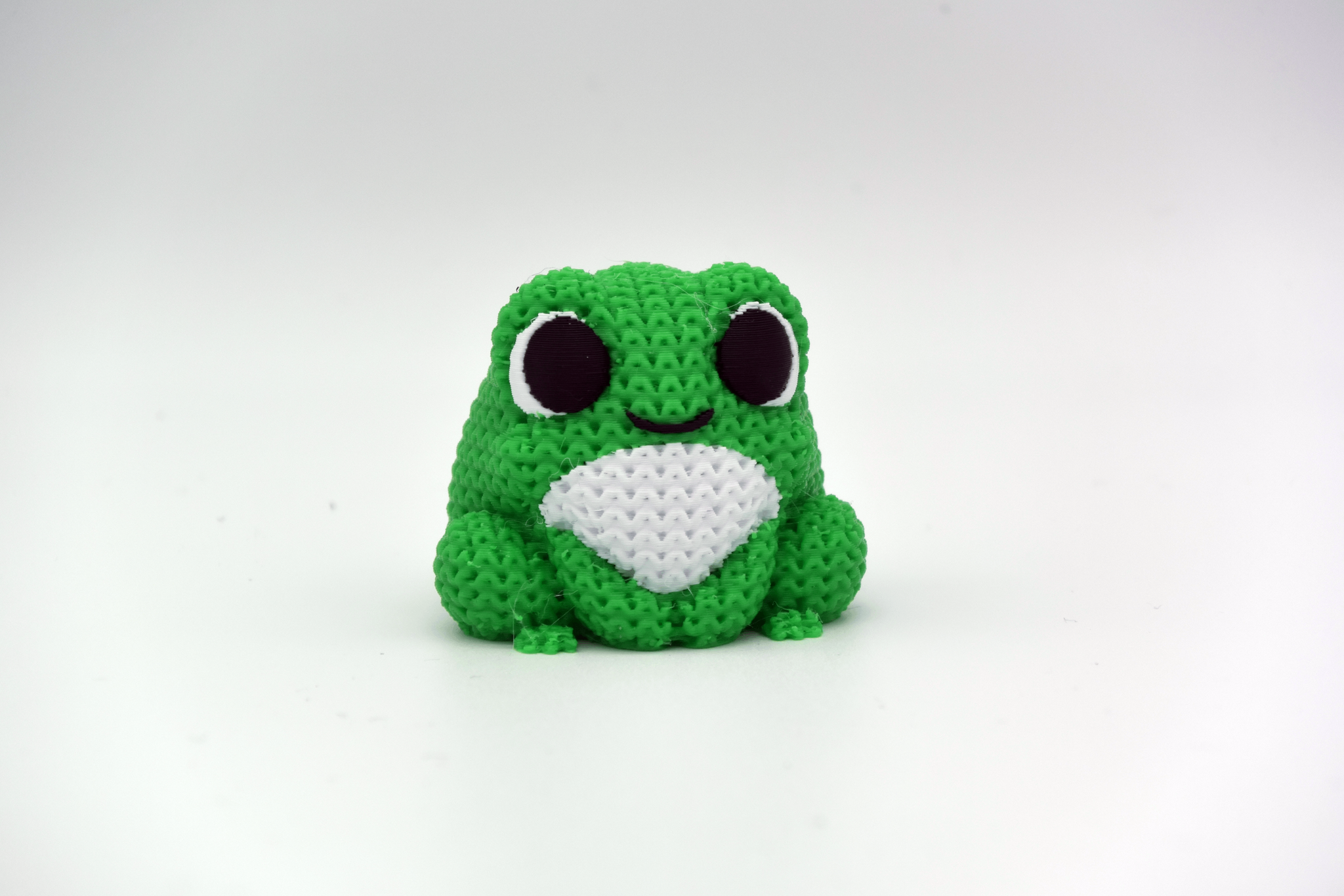 Knitted frog decoration sitting on a wooden shelf next to a small plant in a Scandinavian home interior