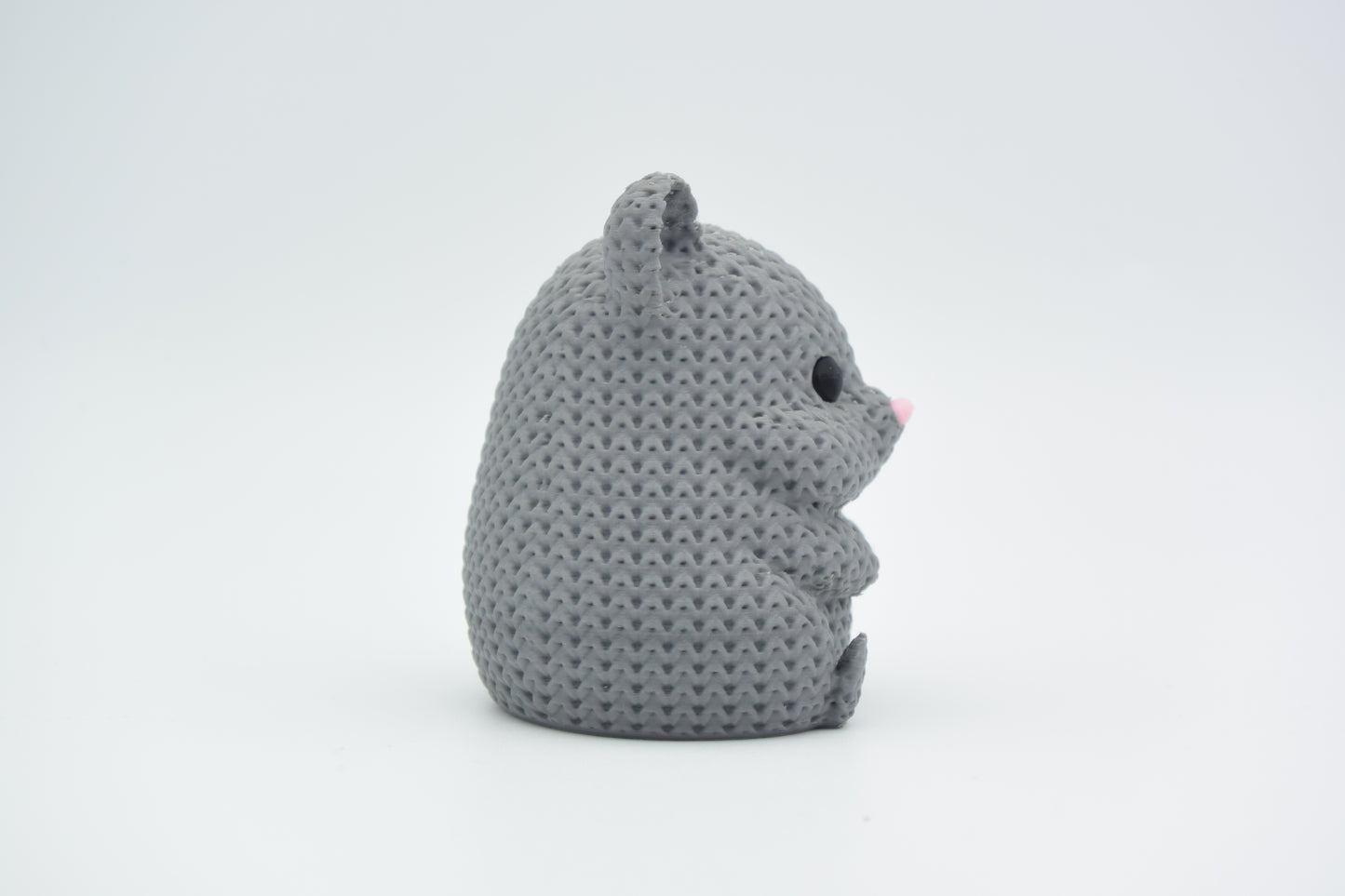 A decorative knitted hamster sitting on a wooden shelf beside a small plant in a Scandinavian home interior