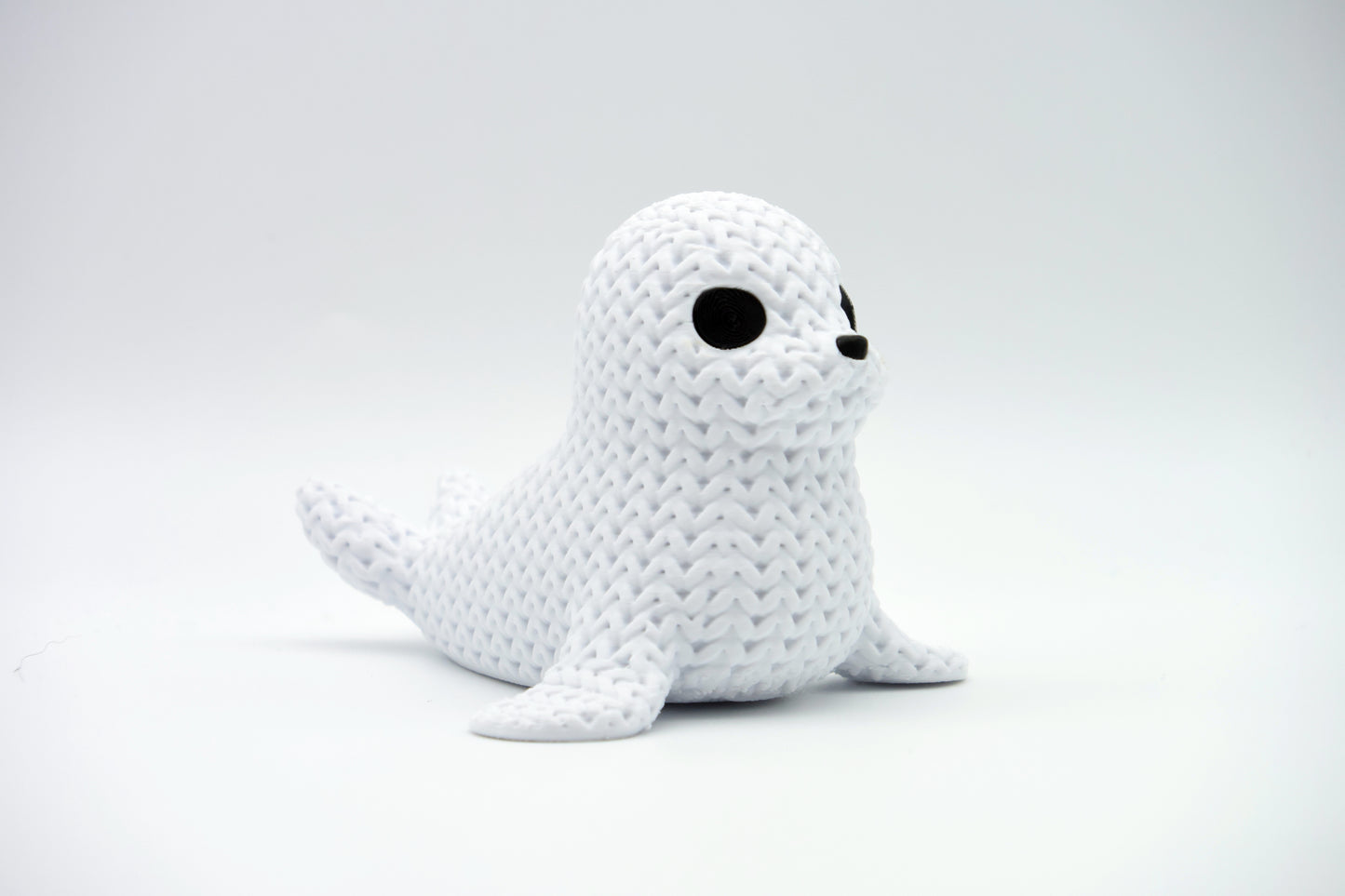 Close-up of a decorative knitted seal figurine with soft crochet-look texture and small dark eyes