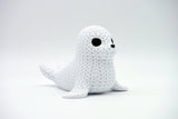 Close-up of a decorative knitted seal figurine with soft crochet-look texture and small dark eyes