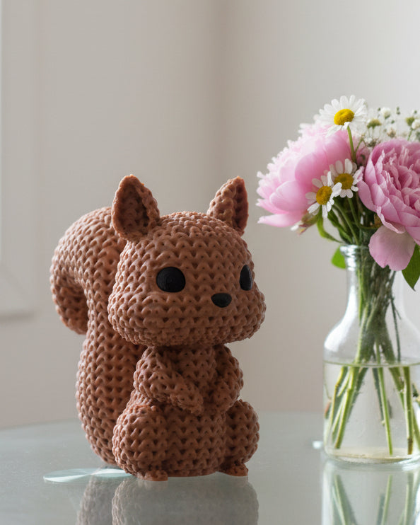 Close-up of a knitted squirrel figurine with a soft crochet-look texture and small glass eyes, 49 DKK