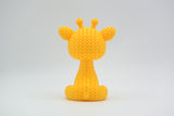 Close-up of a small knitted giraffe figurine with crochet-textured surface and expressive eyes, approx 8 cm tall