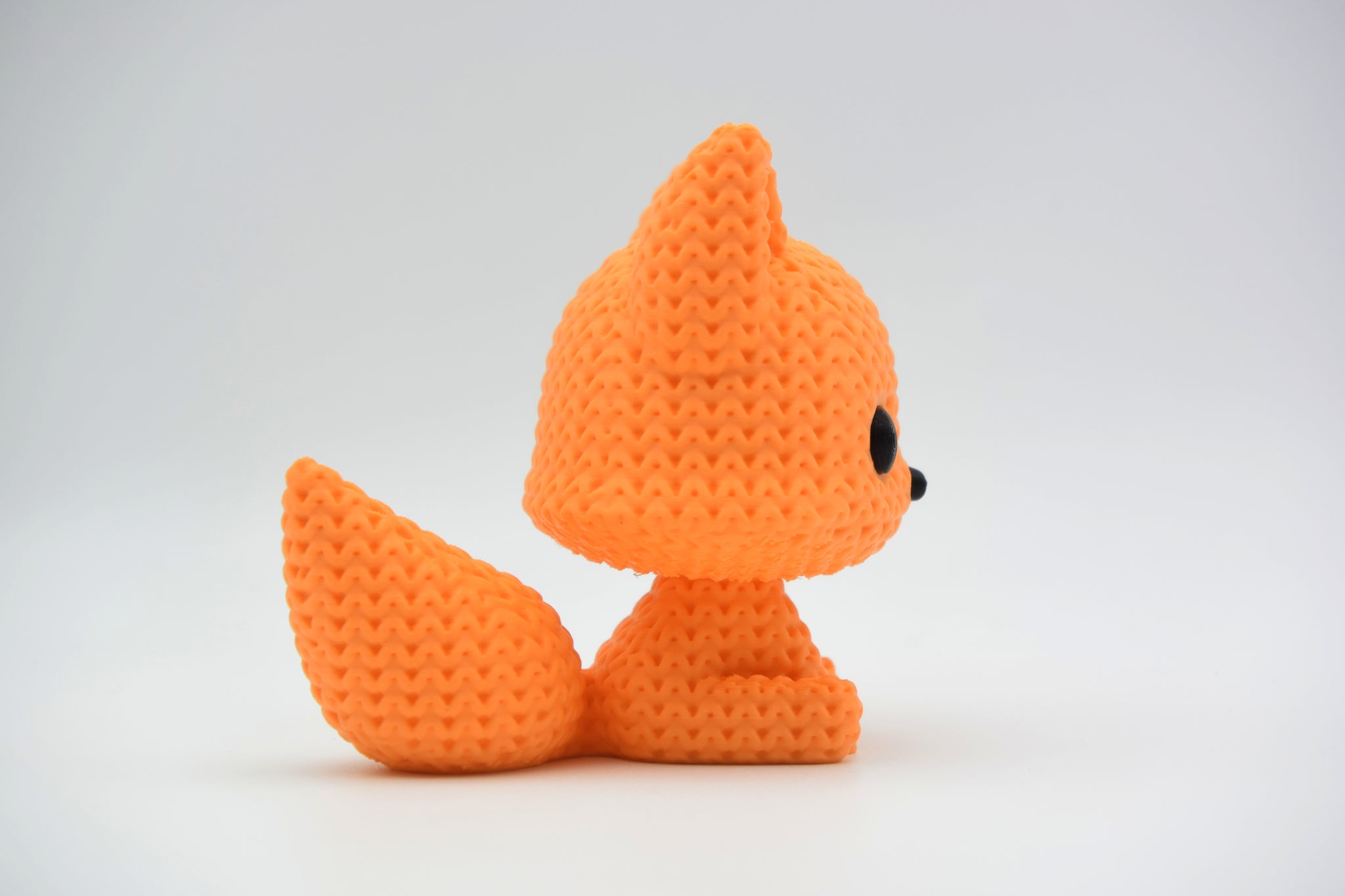 Small knitted fox figurine styled on a wooden shelf next to books and a plant in a Scandinavian home