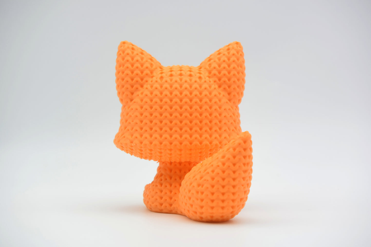 Texture detail of a knitted fox figurine showing the soft, looped crochet-like surface pattern
