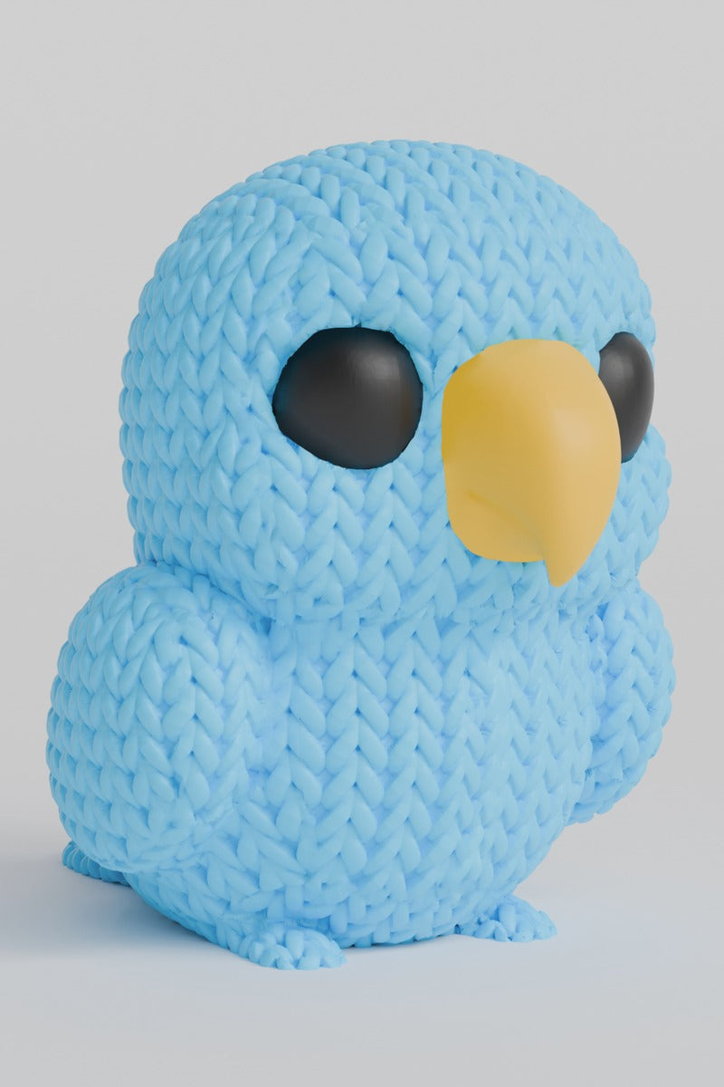 Close-up of a small knitted parrot figurine with textured crochet-like surface and painted eyes, 65 mm tall