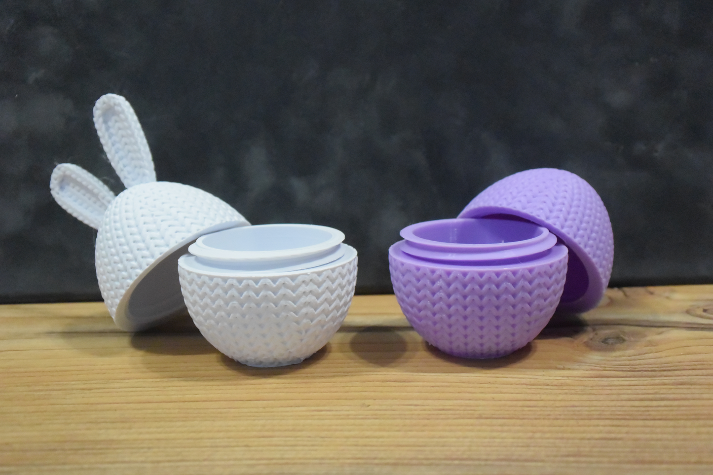 Knitted Easter egg container with bunny ears in pastel pink, standing upright on a white surface, close-up view