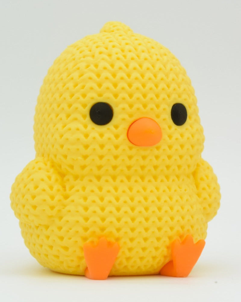 Close-up of a small knitted chick decoration with crochet texture, yellow with orange beak and feet