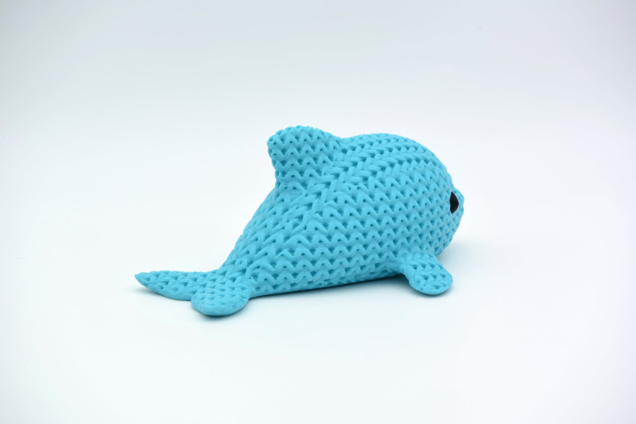 Detail shot of the crochet-look texture on the body of a decorative dolphin figure in grey-blue tones