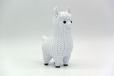 Close-up of a knitted llama figurine with soft crochet-look texture, shown in a neutral cream colour