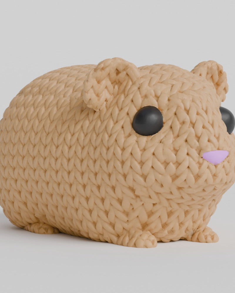 Close-up of a knitted guinea pig figurine with crochet texture, inset eyes and nose, viewed from the front