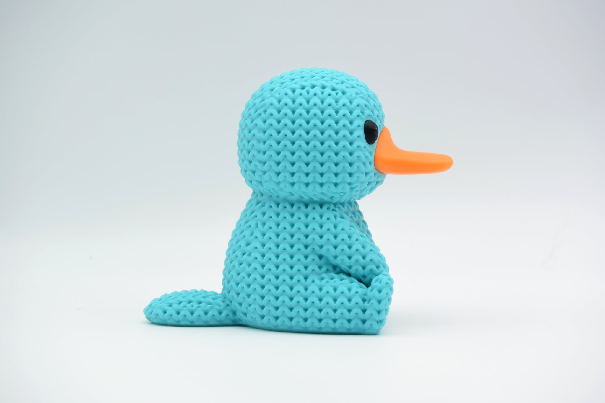 Detail shot of the looped yarn-like surface texture on a knitted platypus decorative figurine