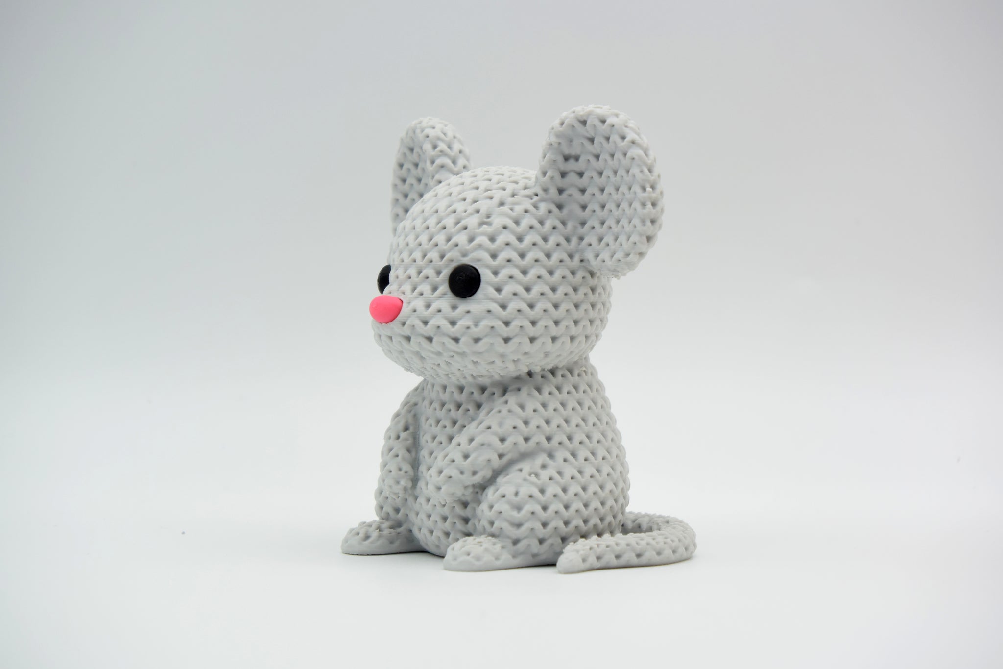 Small knitted mouse decoration placed on a wooden shelf next to a potted plant in a Scandinavian home interior