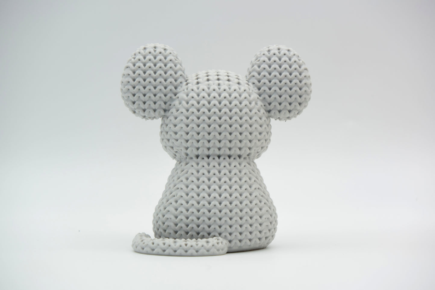 Detail shot of the yarn-like texture on a knitted mouse figure, showing the woven surface pattern up close