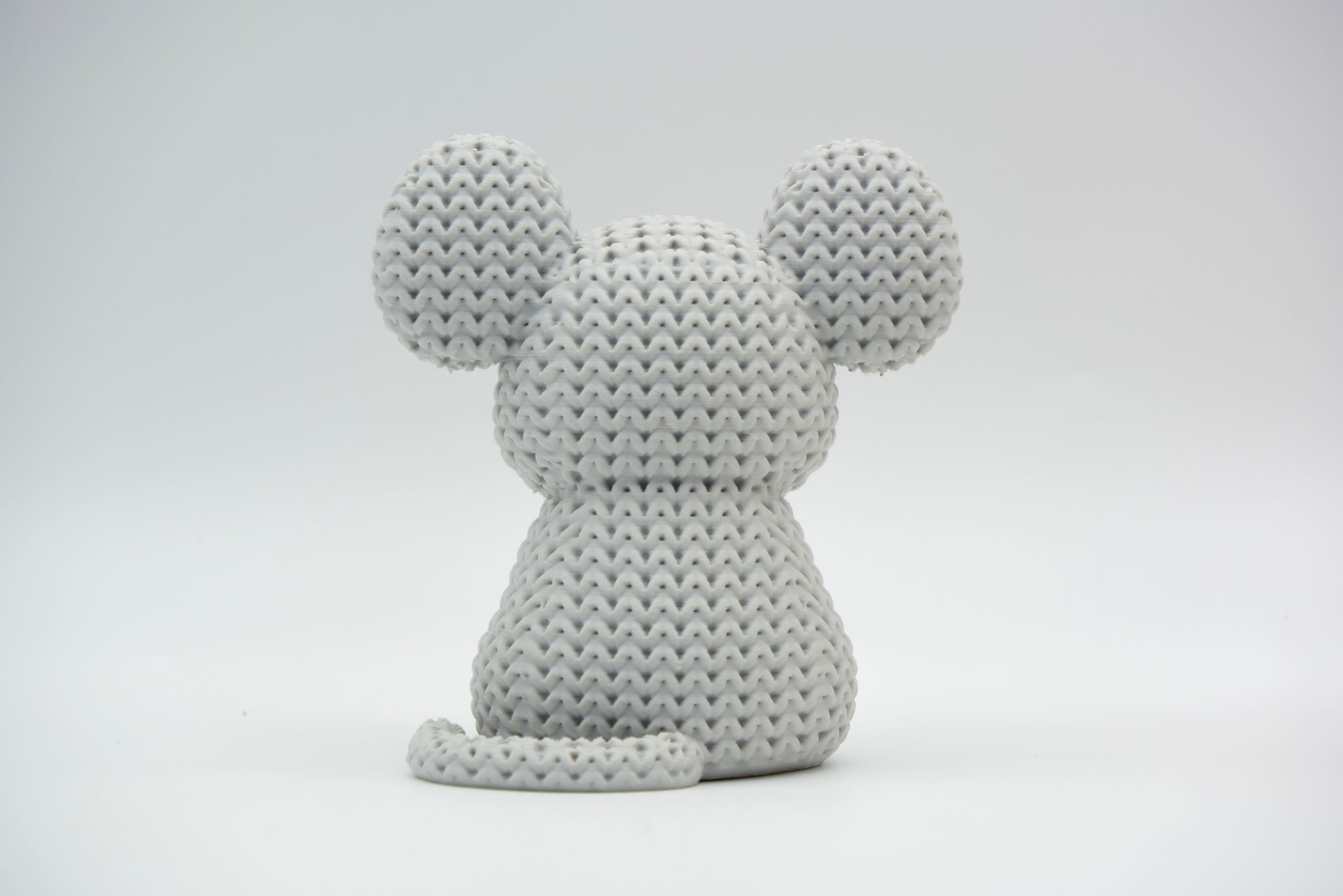Detail shot of the yarn-like texture on a knitted mouse figure, showing the woven surface pattern up close
