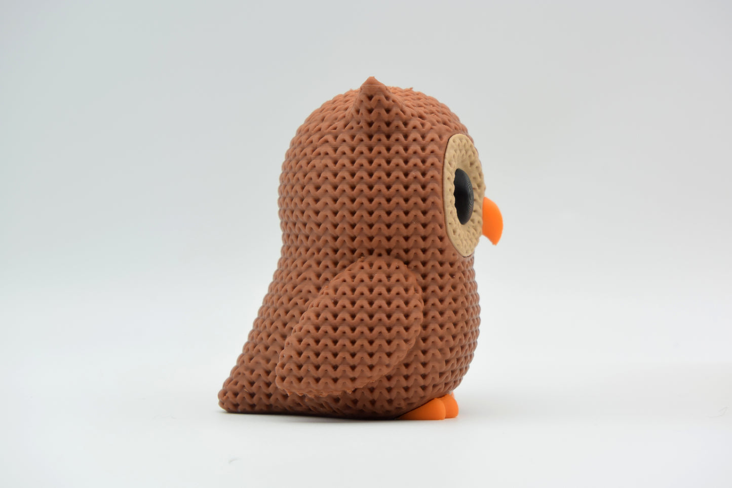 Small knitted owl decoration styled on a wooden shelf next to books and a green plant in a Scandinavian living room