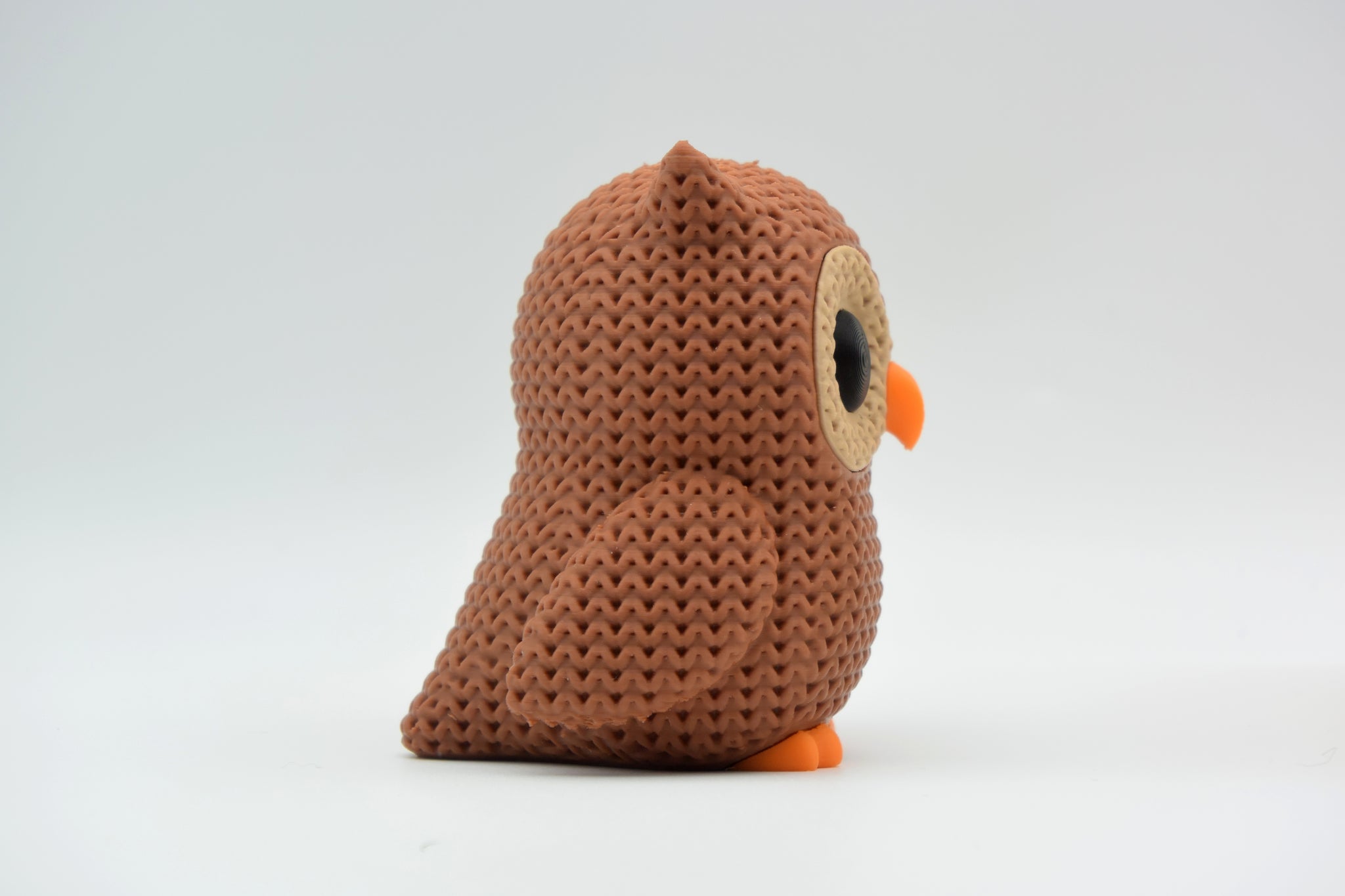 Small knitted owl decoration styled on a wooden shelf next to books and a green plant in a Scandinavian living room