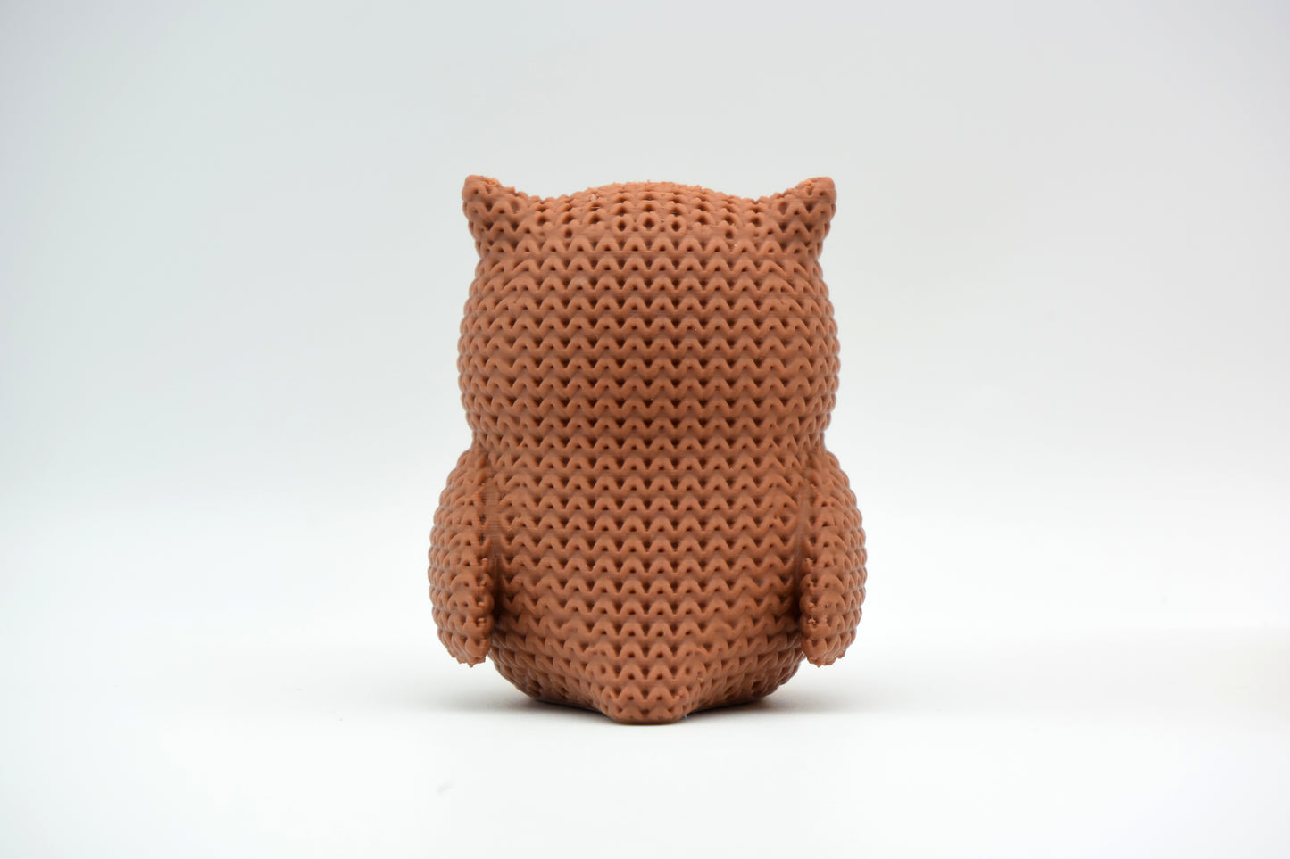 Detail shot of the textured surface of a knitted owl figurine showing the woven crochet-like pattern