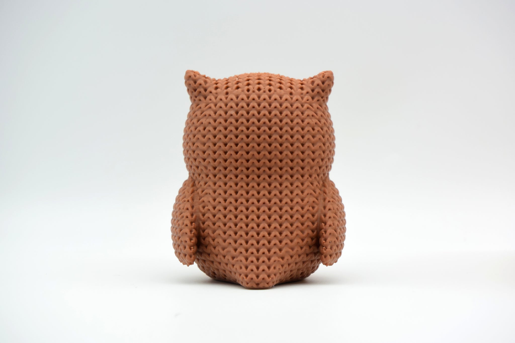 Detail shot of the textured surface of a knitted owl figurine showing the woven crochet-like pattern