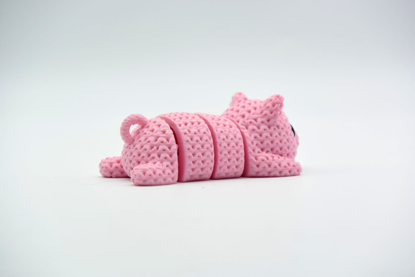 Knitted pig flexi keychain hanging from a set of keys on a wooden table in a bright home setting