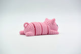 Knitted pig flexi keychain hanging from a set of keys on a wooden table in a bright home setting