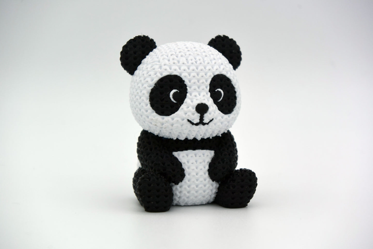 Close-up of a knitted panda figurine showing black and white crochet-look texture, small decorative object