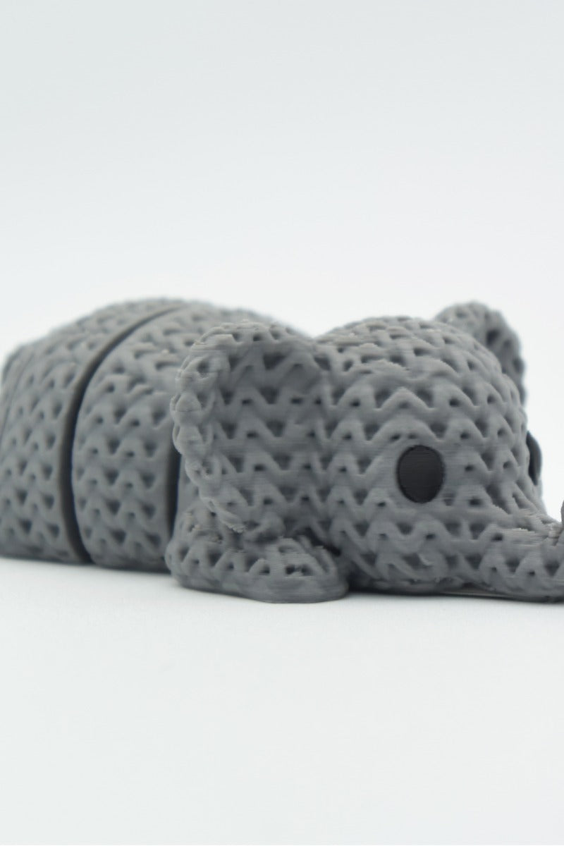 Close-up of a knitted elephant keychain with textured crochet-like surface and articulated body segments
