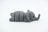 Small knitted elephant keychain resting on a wooden tabletop beside house keys and a linen pouch