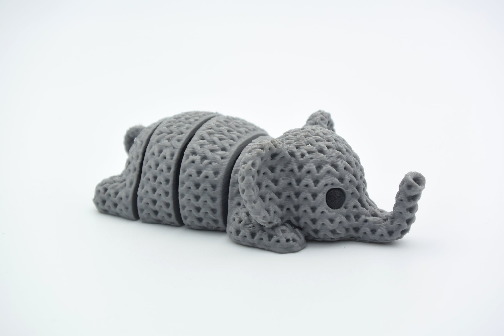 Close-up of a knitted elephant keychain with textured crochet-like surface and articulated body segments