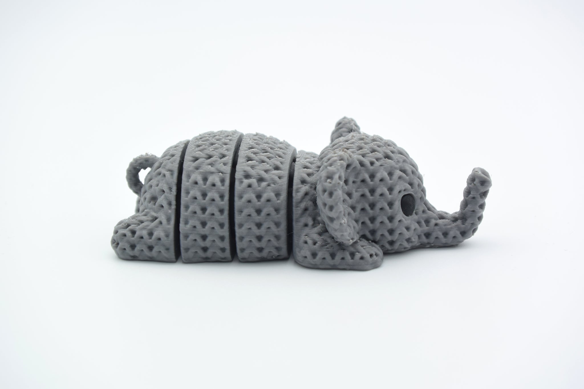Close-up of a knitted elephant keychain with textured crochet-like surface and articulated body segments