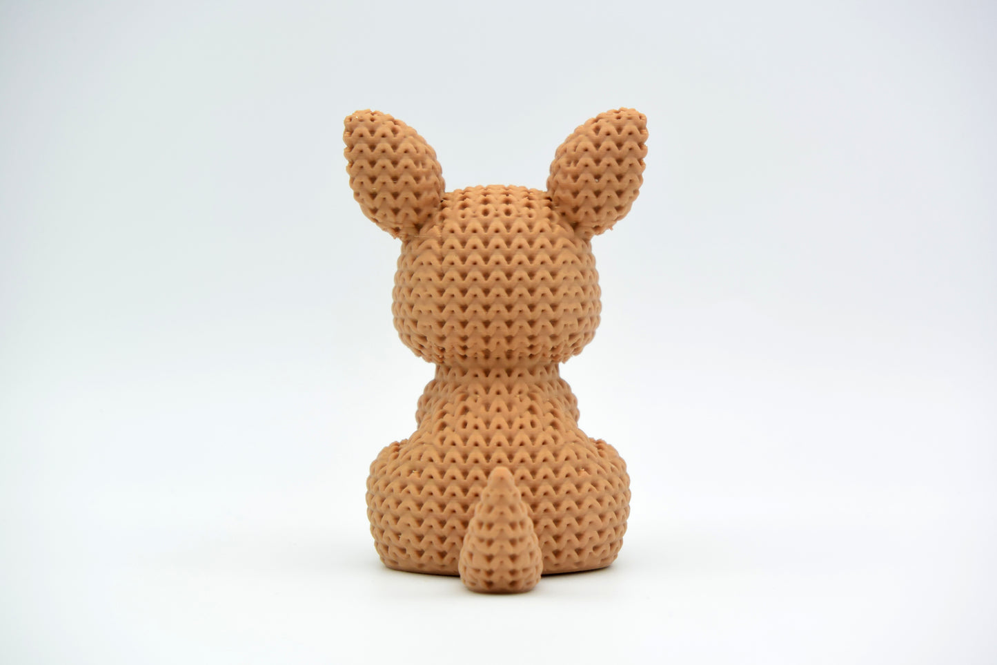 Macro detail of the crochet-look surface texture on a knitted kangaroo figurine, showing soft looped pattern