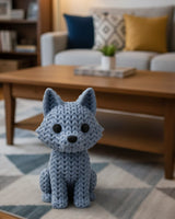 Close-up of a knitted wolf figurine showing crochet-textured surface in warm grey tones, approx 10 cm tall