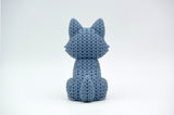 Close-up of a knitted wolf figurine showing crochet-textured surface in warm grey tones, approx 10 cm tall