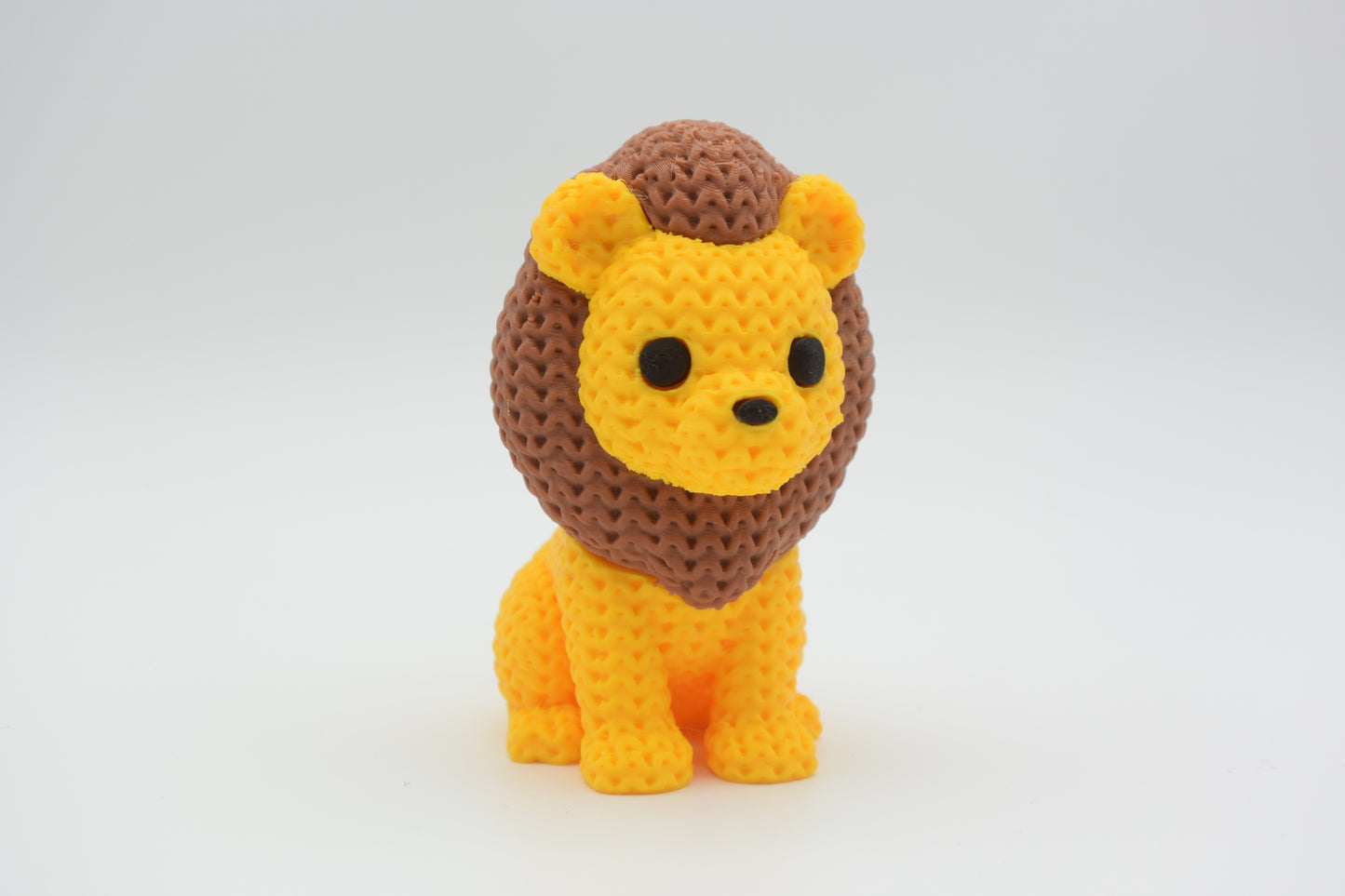 Small knitted lion decorative figure styled on a wooden shelf beside a plant and neutral home accessories