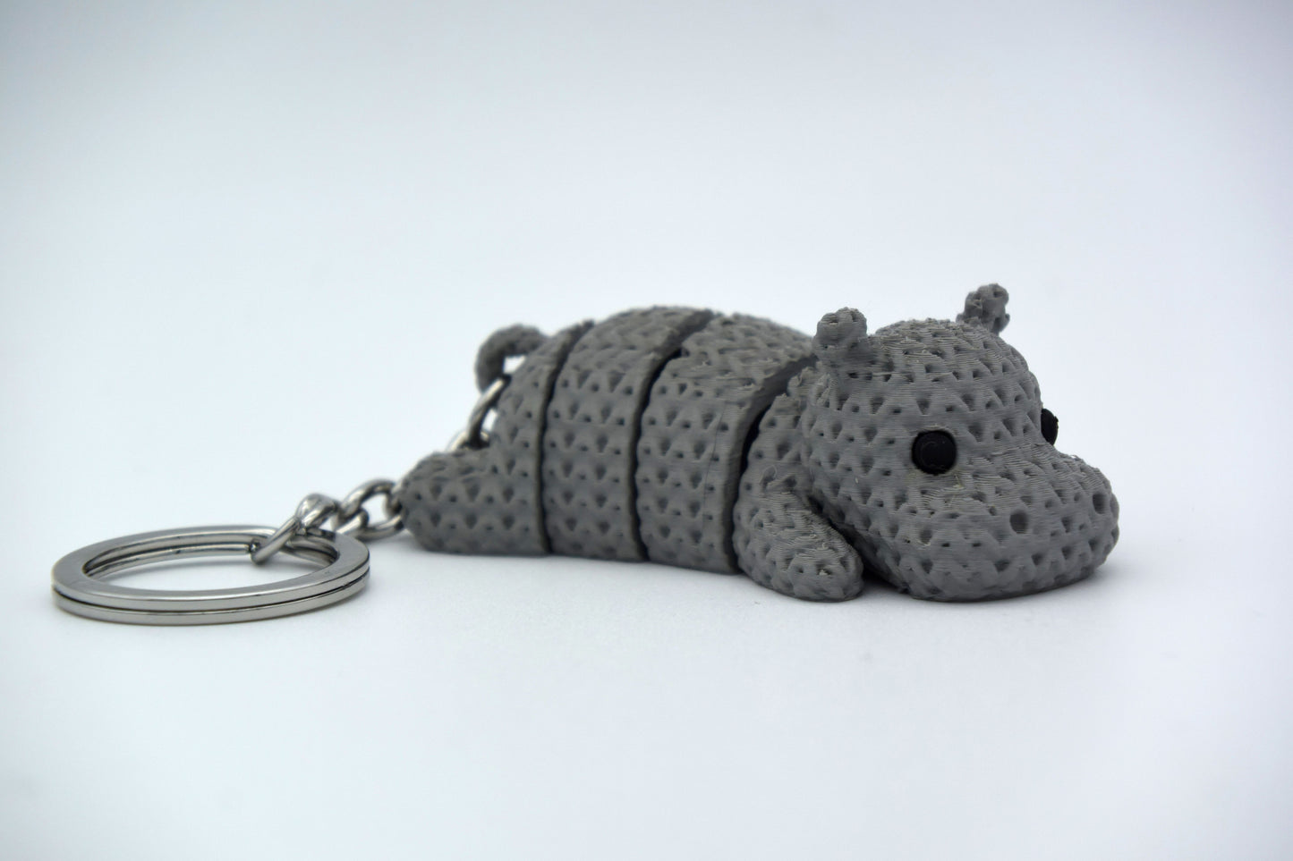 Small knitted hippo decoration placed on a wooden desk beside a plant and a coffee cup