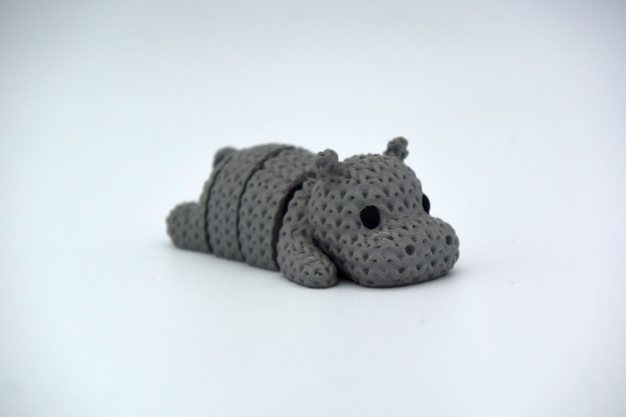 Close-up of a knitted hippo figurine with textured crochet-look surface, photographed on a white background